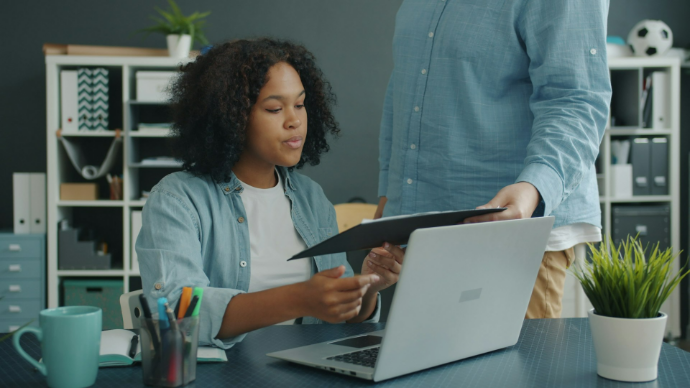 Two colleagues reviewing documents at an office desk.